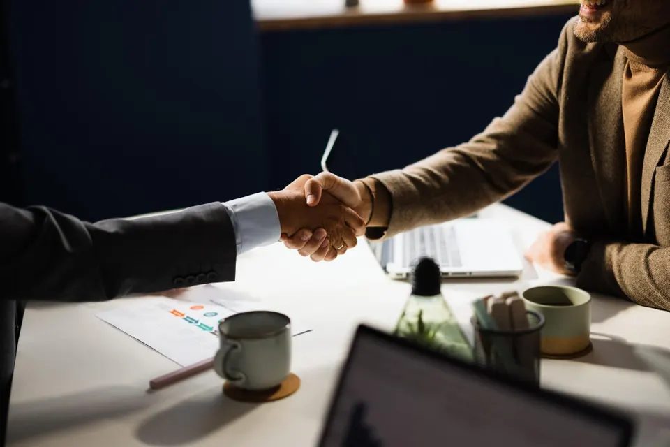 Aperto de mão entre dois profissionais sobre uma mesa de escritório